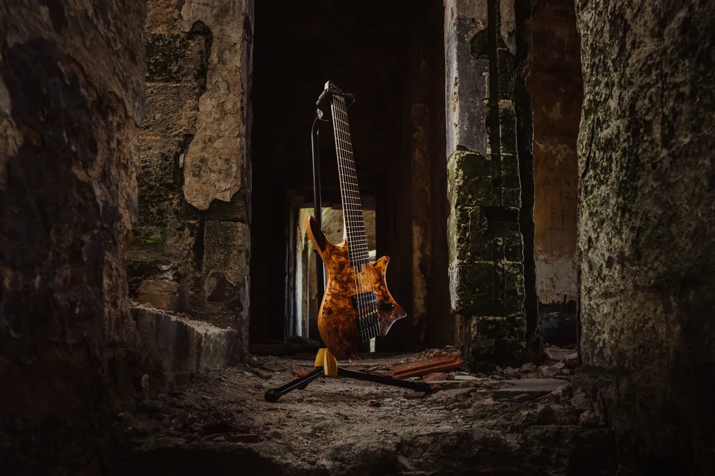 Venere, a headless multiscale guitar with a poplar burl top, standing in the doorway of a ruined building